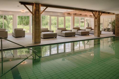 a swimming pool with couches and chairs in a building at Naturhotel MOLIN in San Giovanni in Val Aurina