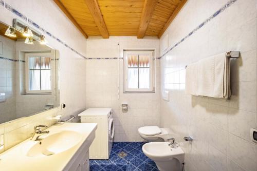 a white bathroom with a sink and a toilet at Kuenz Dolomites App Drau in San Candido