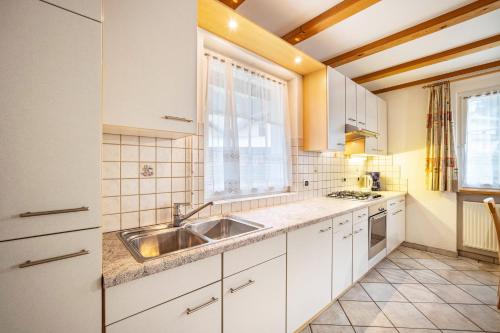 a kitchen with white cabinets and a sink at Kuenz Dolomites App Drau in San Candido