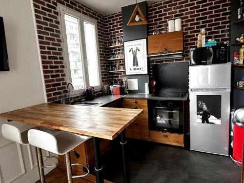 une cuisine avec une table en bois et un mur en briques dans l'établissement Appartement Confortable et Spacieux Boulogne-Billancourt, à Boulogne-Billancourt