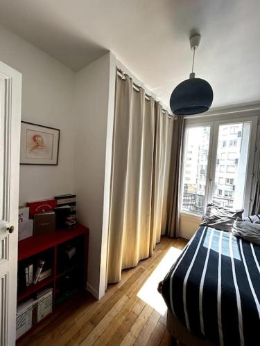 - une chambre avec un lit et une grande fenêtre dans l'établissement Appartement Confortable et Spacieux Boulogne-Billancourt, à Boulogne-Billancourt