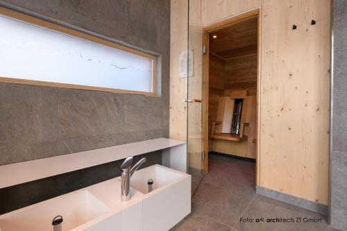 ein Bad mit einem Waschbecken und einem Spiegel in der Unterkunft Apart & Pension Wassermann inklusive Sommerbergbahnticket in Tannheim