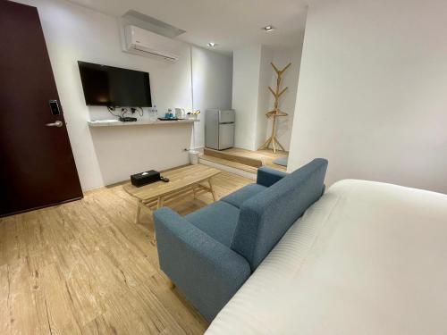 Habitación con cama, sofá azul y TV. en 森浩文旅, en Taipéi