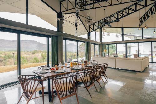 Un comedor con una mesa larga y sillas. en LohonoStays Villa Trisara, en Lonavala
