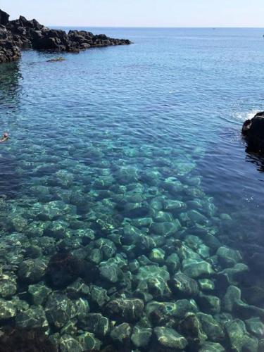 a large body of clear water with rocks andploadploadploadploadploadpload at Ambra in Stazzo