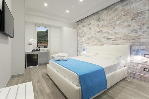 una camera da letto con un grande letto bianco e un muro di pietra di Vhome a Sorrento