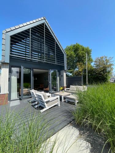 a house with white chairs and a patio at Lutz Watervilla's Balk in Balk