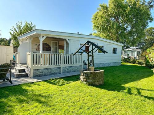 a mobile home with a porch and a statue in the yard at Chalet 513 op Recreatiepark De Wielen in Sint Maarten