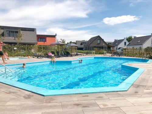 a swimming pool with people in the water at Chalet 513 op Recreatiepark De Wielen in Sint Maarten