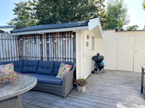 a patio with a blue couch and a grill at Chalet 513 op Recreatiepark De Wielen in Sint Maarten