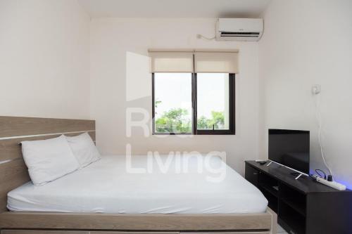 1 dormitorio con 1 cama blanca y TV en RedLiving Apartemen EcoHome - DeLouvre Tower A Suginoki, en Nalagat