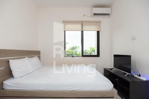 a bedroom with a white bed and a tv at RedLiving Apartemen RQ at Ecohome Citra Raya in Nalagat