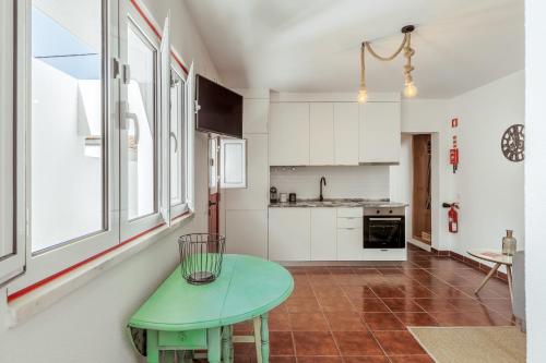 una cocina con armarios blancos y una mesa verde en Pinheirinha Guest House en Alpiarça