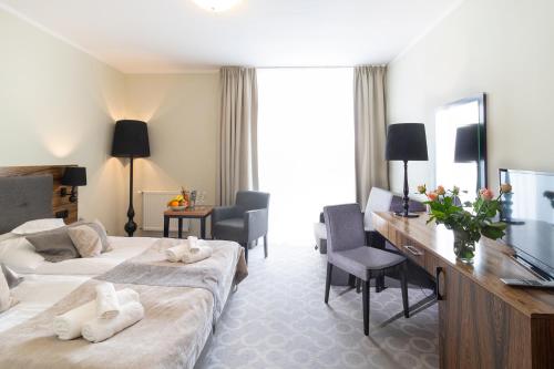 ポゴジェリツァにあるSandra Spa Pogorzelica & Aquaparkのベッド2台とデスクが備わるホテルルームです。