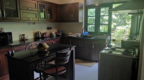 una cucina con armadi in legno, tavolo e piano cottura di Airport Gateway Residence a Negombo