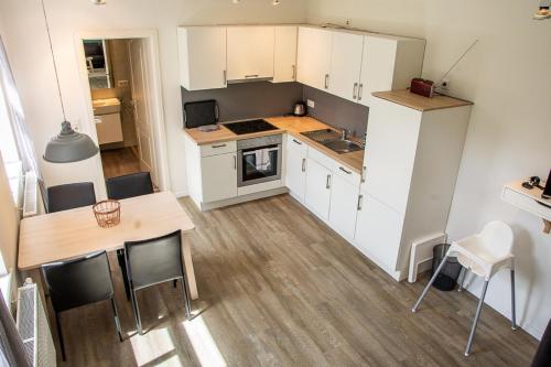 een keuken met witte kasten en een tafel en stoelen bij Atelierhaus Glücksburg Sandwig in Glücksburg