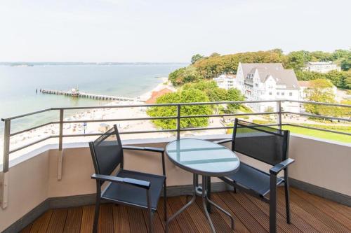 Una mesa y sillas en un balcón con vista al agua. en Förde-Lodge, en Glücksburg