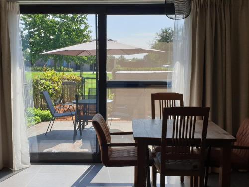 ein Esszimmer mit einem Tisch, Stühlen und einem Sonnenschirm in der Unterkunft Het Zonnetje -Vakantiewoning en Bed and Breakfast in Dilsen-Stokkem