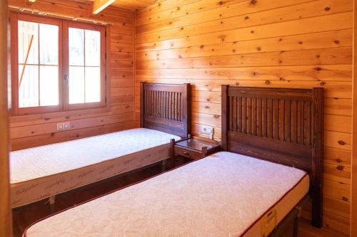 a bedroom with two beds in a log cabin at ALBERGUE CONTRERAS in Minglanilla