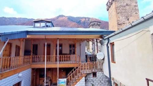 een groot huis met een balkon met bergen op de achtergrond bij Sunny in Mestia