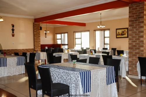 comedor con mesas y sillas y ropa de cama blanca y azul en Meet Mekaar Resorts - Nquthu Hotel, en Nqutu