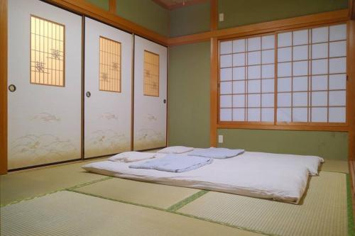 una camera con un letto in una stanza con finestre di 四万十川傍にある日本家屋まるごと「貸切宿　ほとり」 a Shimanto