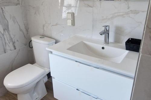 a white bathroom with a toilet and a sink at Le Rocher YourHostHelper in Fontanil-Cornillon