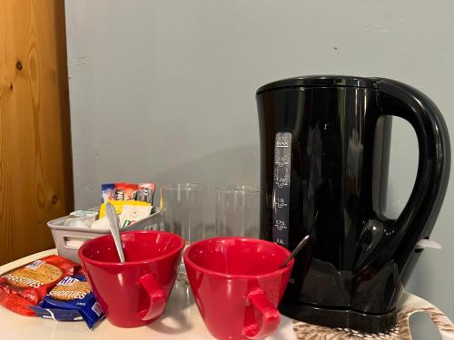 a black coffee pot and three red cups on a counter at Modern Rooms with SELF Check-In The Castle, Coldstream in Coldstream