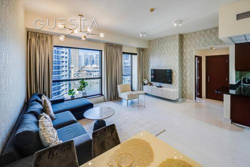 a living room with a blue couch and a large window at Bahar Residence, JBR, Dubai Marina in Dubai