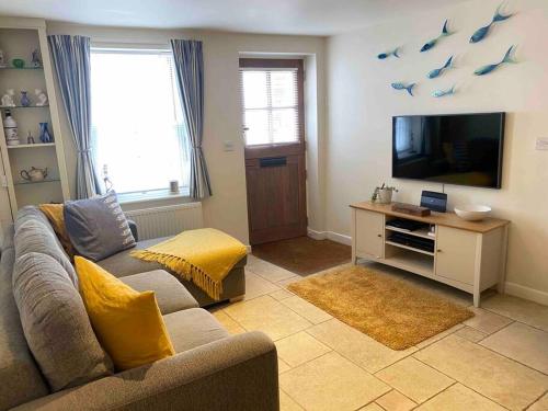a living room with a couch and a flat screen tv at High end cottage in amazing location. Only 1 minute from the sea! Beautifully decorated 3 level home. 5* reviews in Lyme Regis
