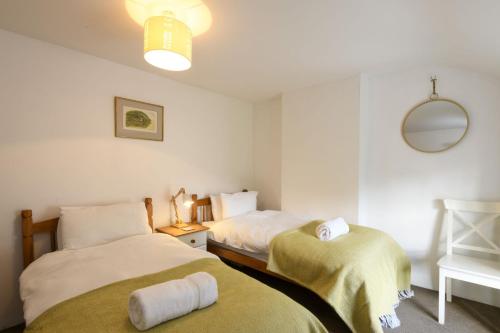 a bedroom with two beds and a mirror at April Cottage in Saint Just in Roseland