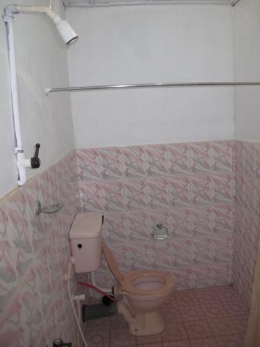 a bathroom with a toilet and a pink tiled wall at Gopalapuram Guest House in Nilaveli