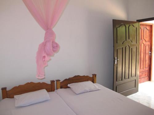 a bedroom with a bed with a pink stuffed animal on the wall at Gopalapuram Guest House in Nilaveli