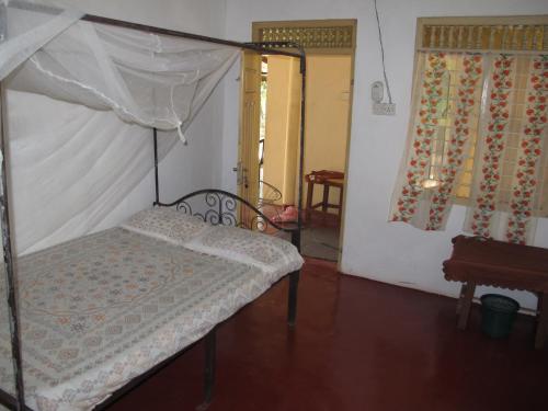 a bedroom with a bed with a canopy at Gopalapuram Guest House in Nilaveli