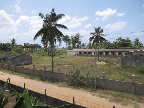 a building with a fence and palm trees at Gopalapuram Guest House in Nilaveli