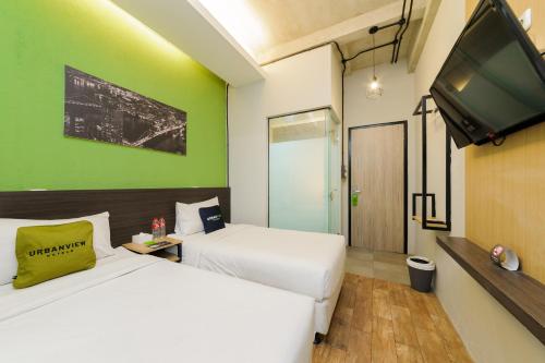 a hotel room with two beds and a flat screen tv at Sans Stay Caverna Gandaria in Jakarta
