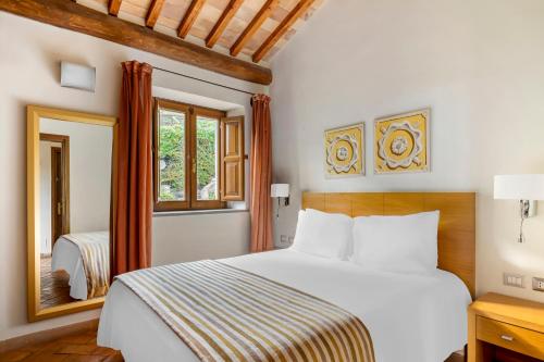 1 dormitorio con cama blanca y espejo en Palazzo Catalani Resort, en Soriano nel Cimino