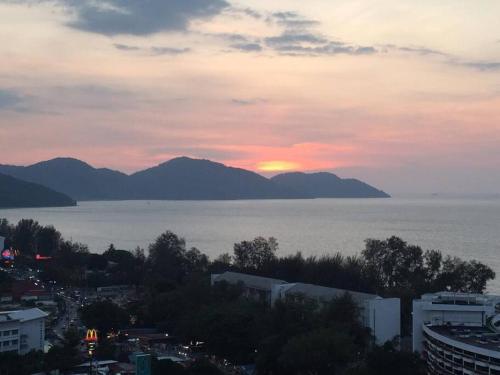 a sunset over the water with mountains in the background at New! Batu Ferringhi Seaview Cozy Condo, Penang in Batu Ferringhi