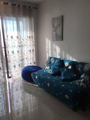 a blue couch in a living room with a window at New! Batu Ferringhi Seaview Cozy Condo, Penang in Batu Ferringhi