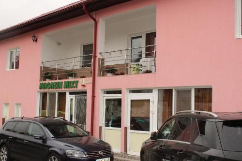 two cars parked in front of a pink building at Casa Dănuț in Reşiţa