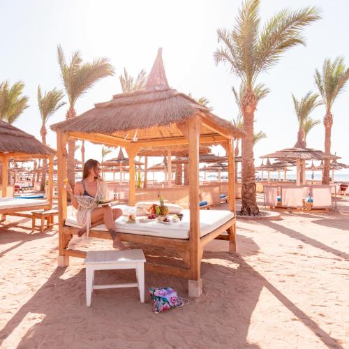 a woman sitting in a gazebo on the beach at Pickalbatros Palace - Aqua Park Hurghada in Hurghada