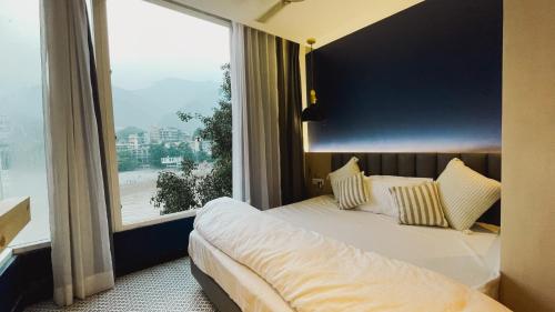 a bedroom with a bed and a large window at Joey's By The Ganges in Rishīkesh