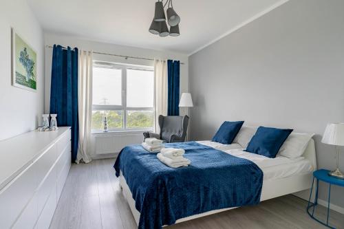 a bedroom with a bed and a chair and a window at Symphony Baltica Towers Apartamenty in Gdańsk
