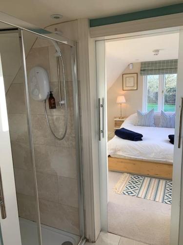 a bedroom with a bed and a glass shower at Annexe near Malmesbury / Tetbury in Hankerton