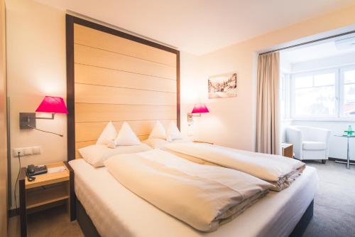 Cama grande en habitación de hotel con ventana en Hotel Enzian - Adults Only en Obertauern