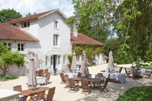a patio with tables and umbrellas in front of a building at Logis La Source Bleue in Gudmont