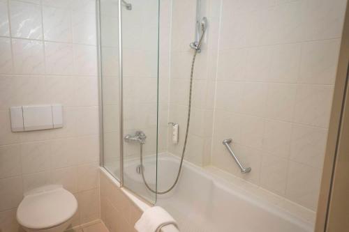 a bathroom with a shower with a toilet and a sink at Atomis Hotel Munich Airport by Mercure in Oberding