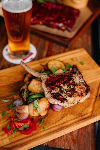 a wooden plate with meat and vegetables and a glass of beer at SLEEP WELL 1999 in Tychy