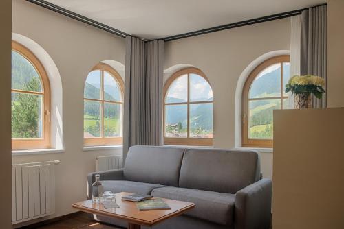 a living room with a couch and three windows at Naturhotel MOLIN in San Giovanni in Val Aurina