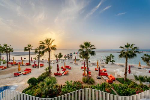 a view of a beach with chairs and palm trees at voco Dubai Monaco, the Heart of Europe by IHG in Dubai
